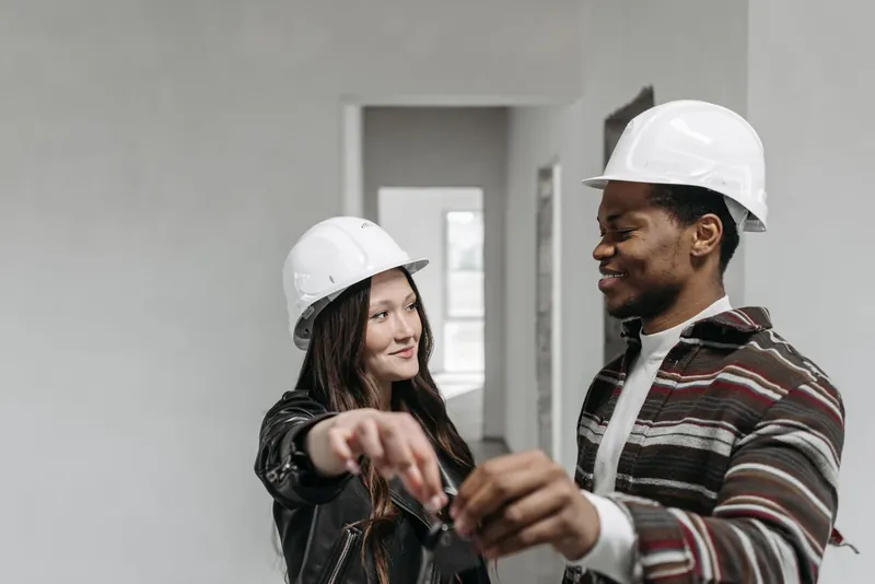 Two builders in hard hats sharing keys on site