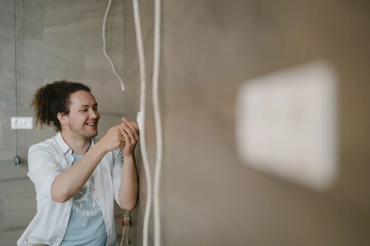 A Lumenfield electrician feeding new cable into a chased wall
