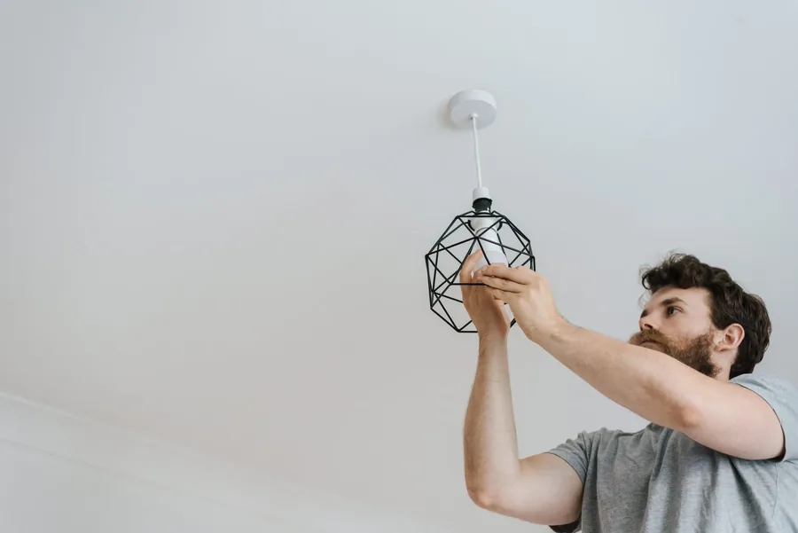 An electrician hanging a pendant light from a ceiling rose