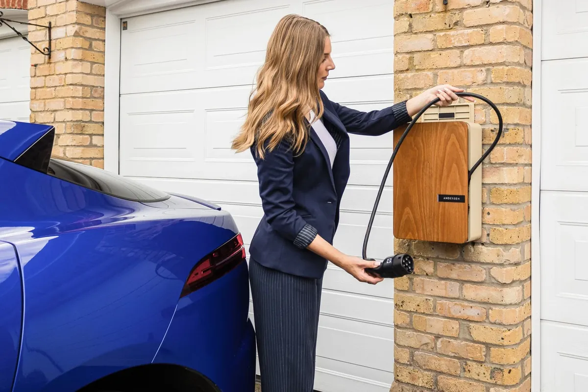 A homeowner plugging her car into a wall mounted charger by the garage
