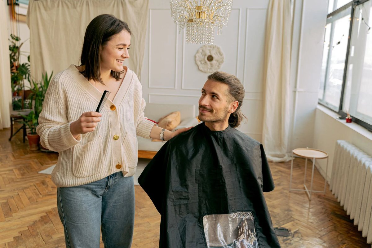 A stylist talking a client through her cut