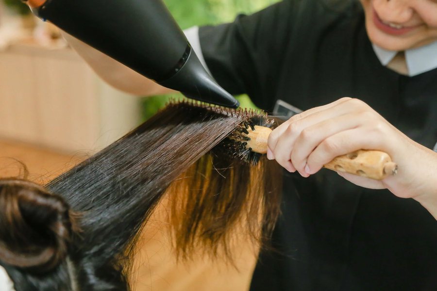 A stylist blow drying long hair
