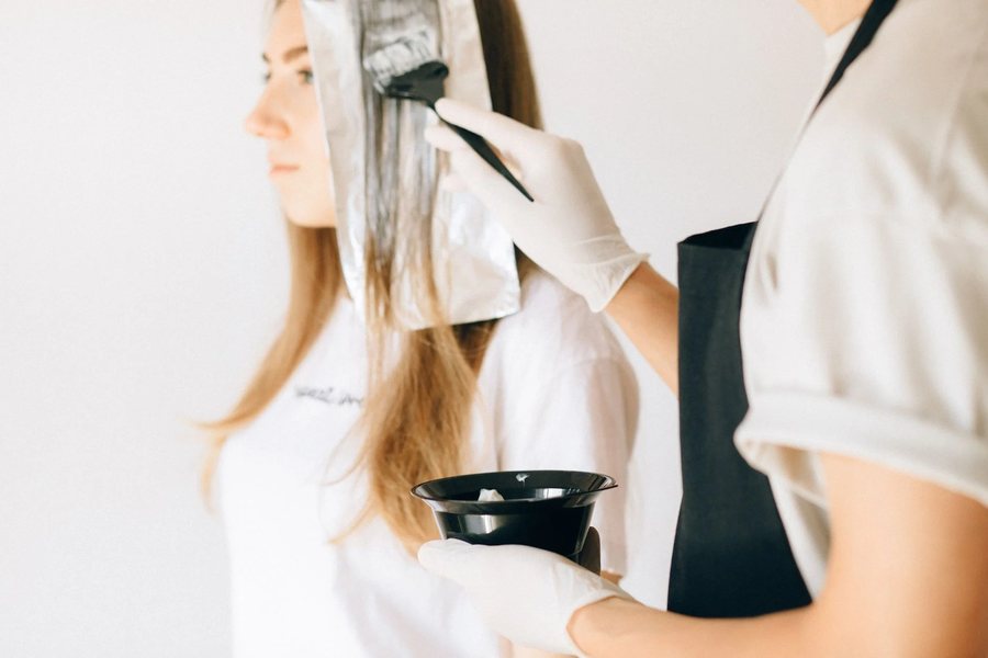 A colourist applying hair colour with a brush