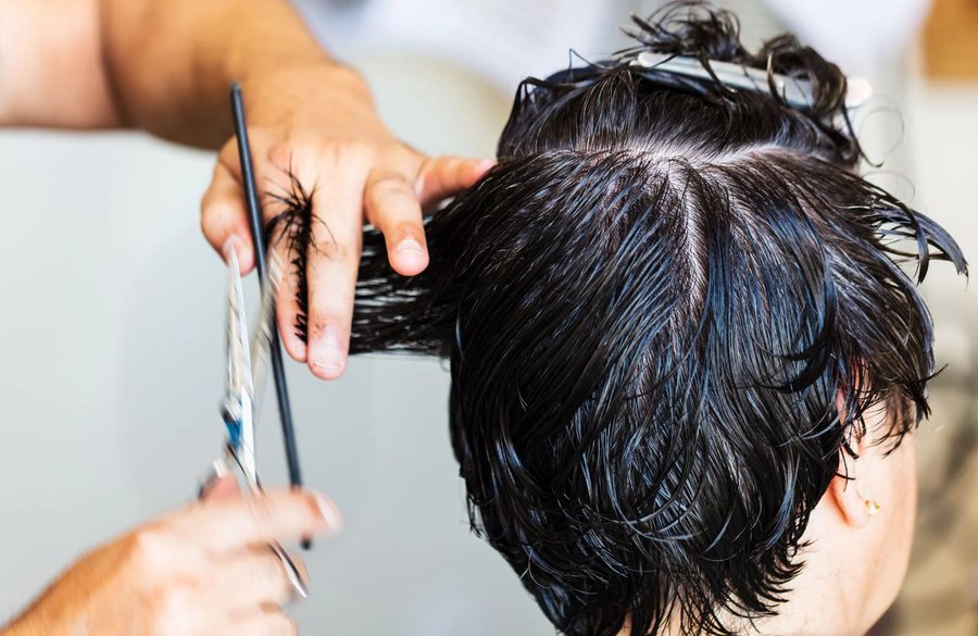 Scissors cutting through dark hair