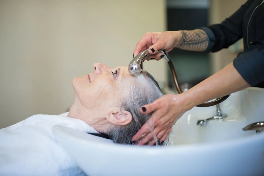 A client having her hair washed at the basin