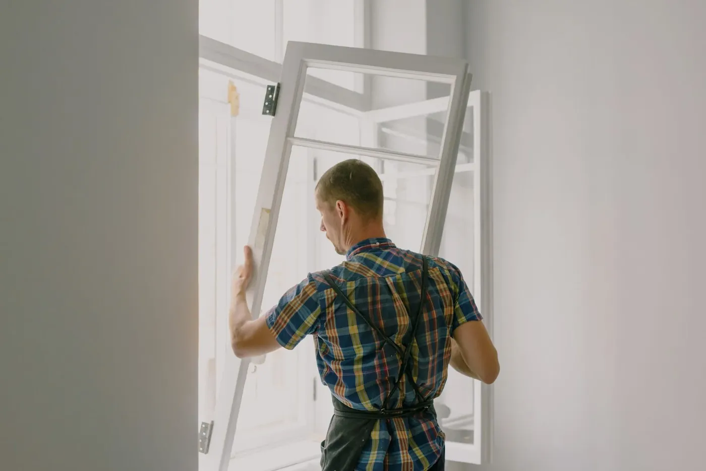 A Mullion and Sill fitter lifting a new window frame into place