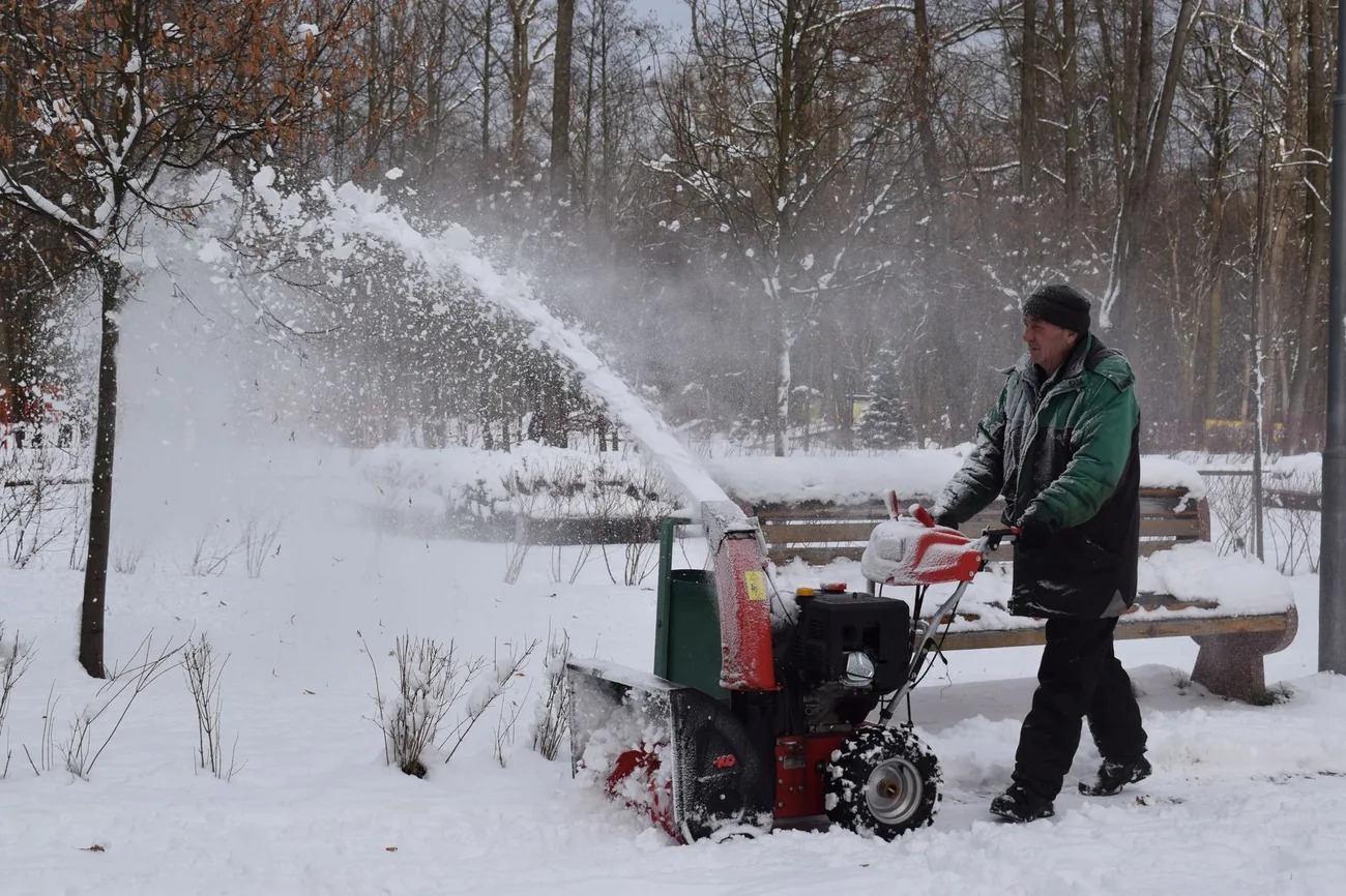 A snow blower throwing snow clear of a path