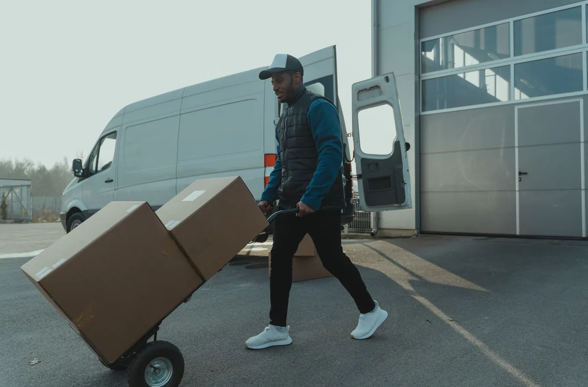 A mover with a sack truck beside a loaded van