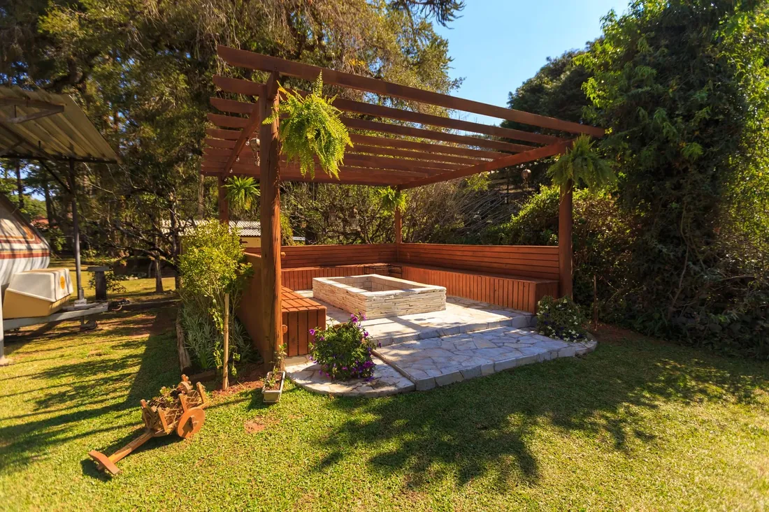 A timber pergola over a fire pit and seating beside a lawn