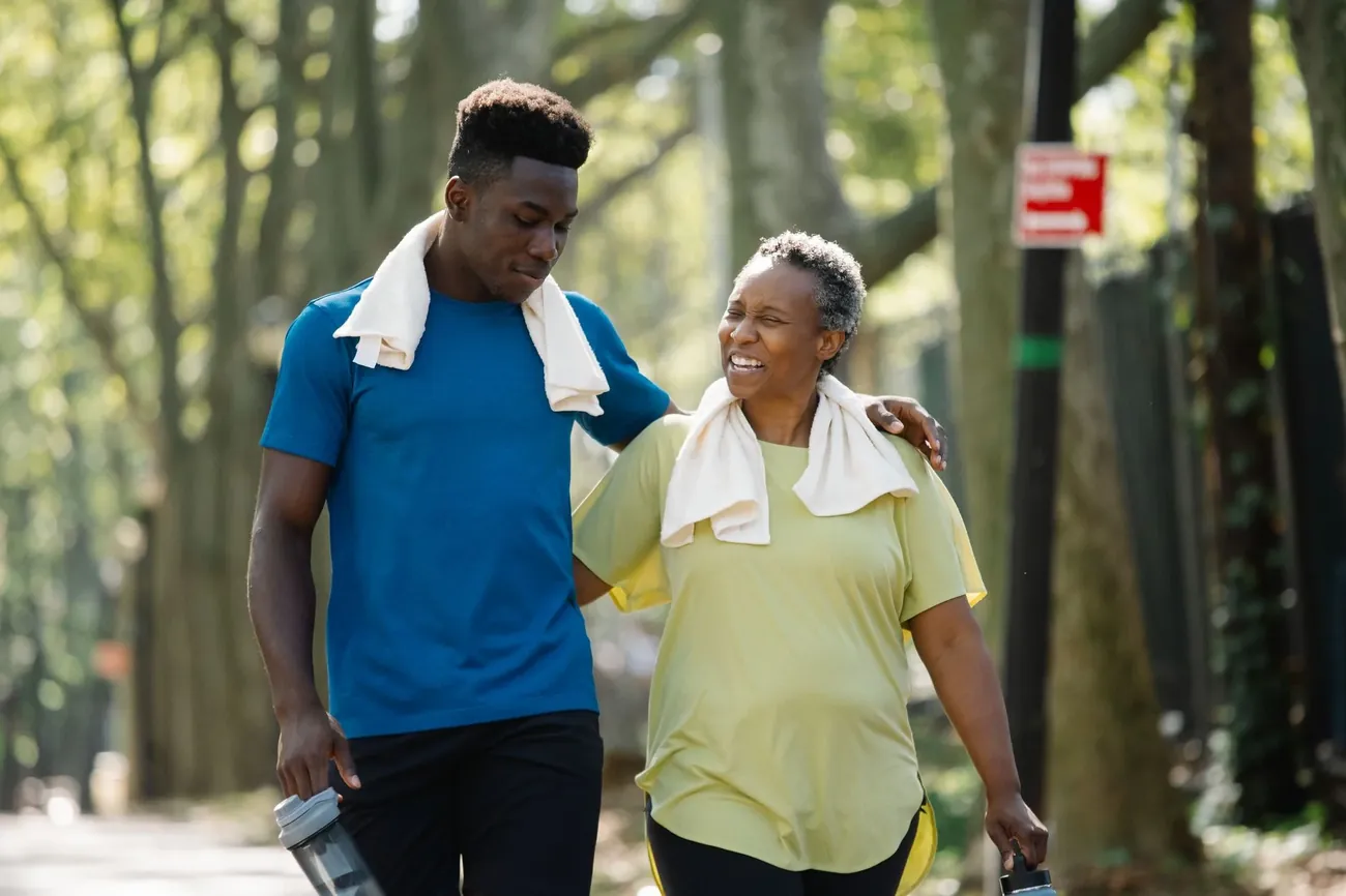 A young man and an older woman laughing together on a walk in the park
