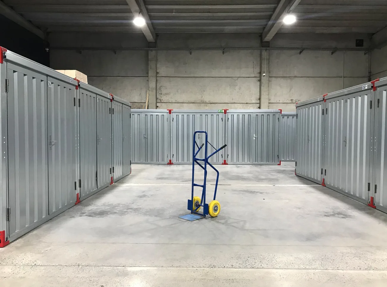 A clean empty storage unit with a sack truck