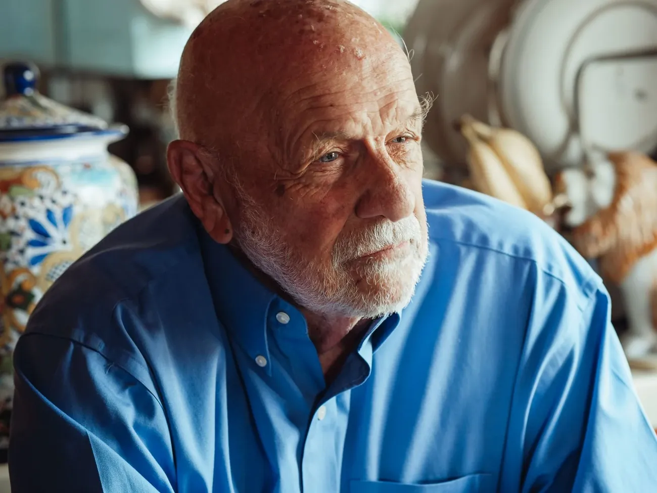 An older man in a blue shirt listening closely