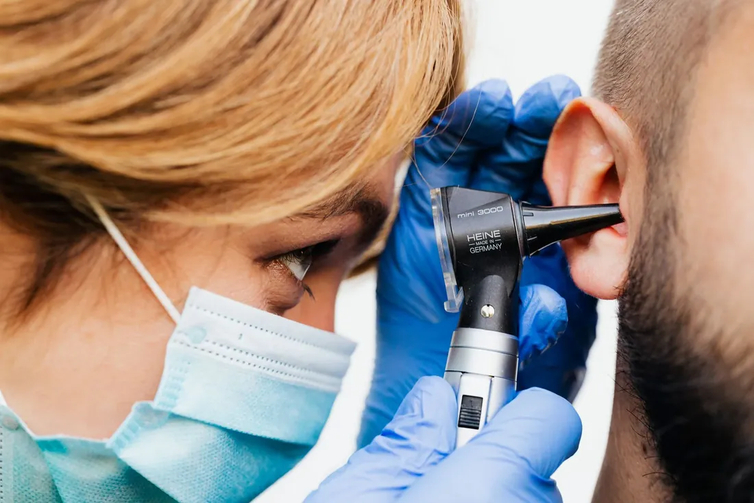 An audiologist looking into a patient's ear with an otoscope