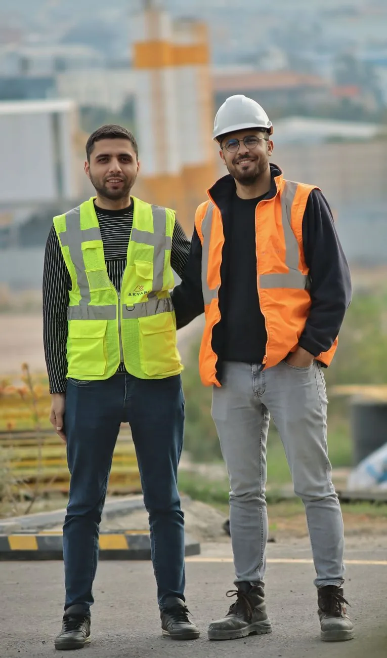 Two operatives in high visibility gear beside a property