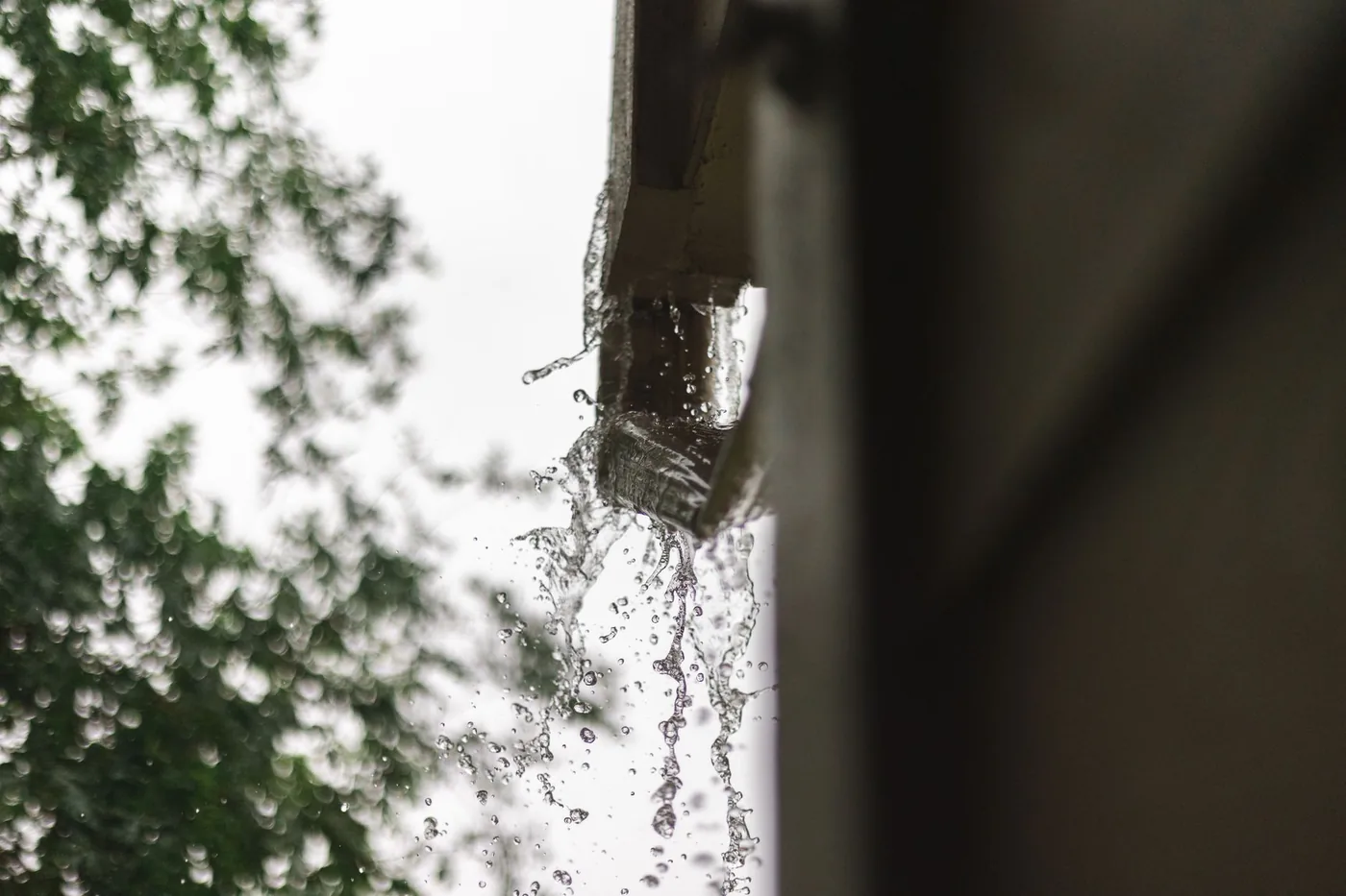 Water running off a roof corner onto the wall below