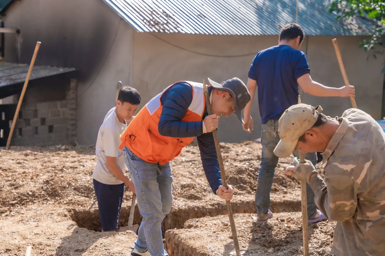A crew digging a trench beside a house foundation
