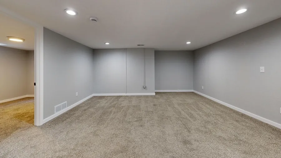 A finished, carpeted basement with grey walls
