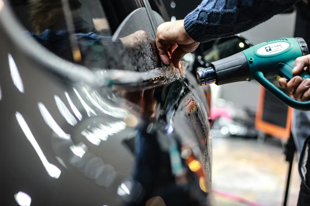 A heat gun shrinking film to the curve of a window