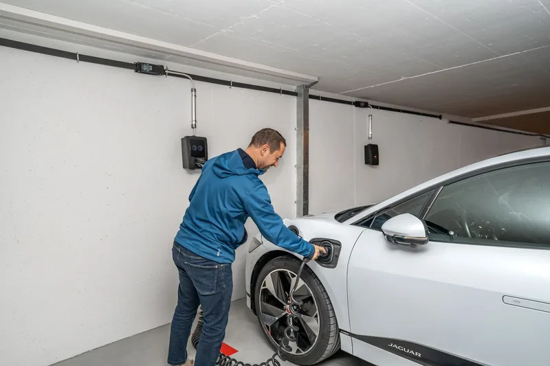A homeowner plugging an electric car into a garage charger
