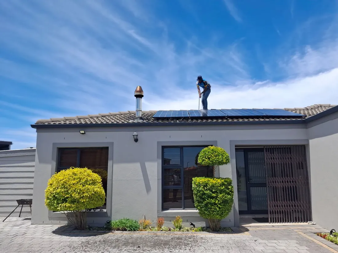 A single storey stucco house with an installer on the roof