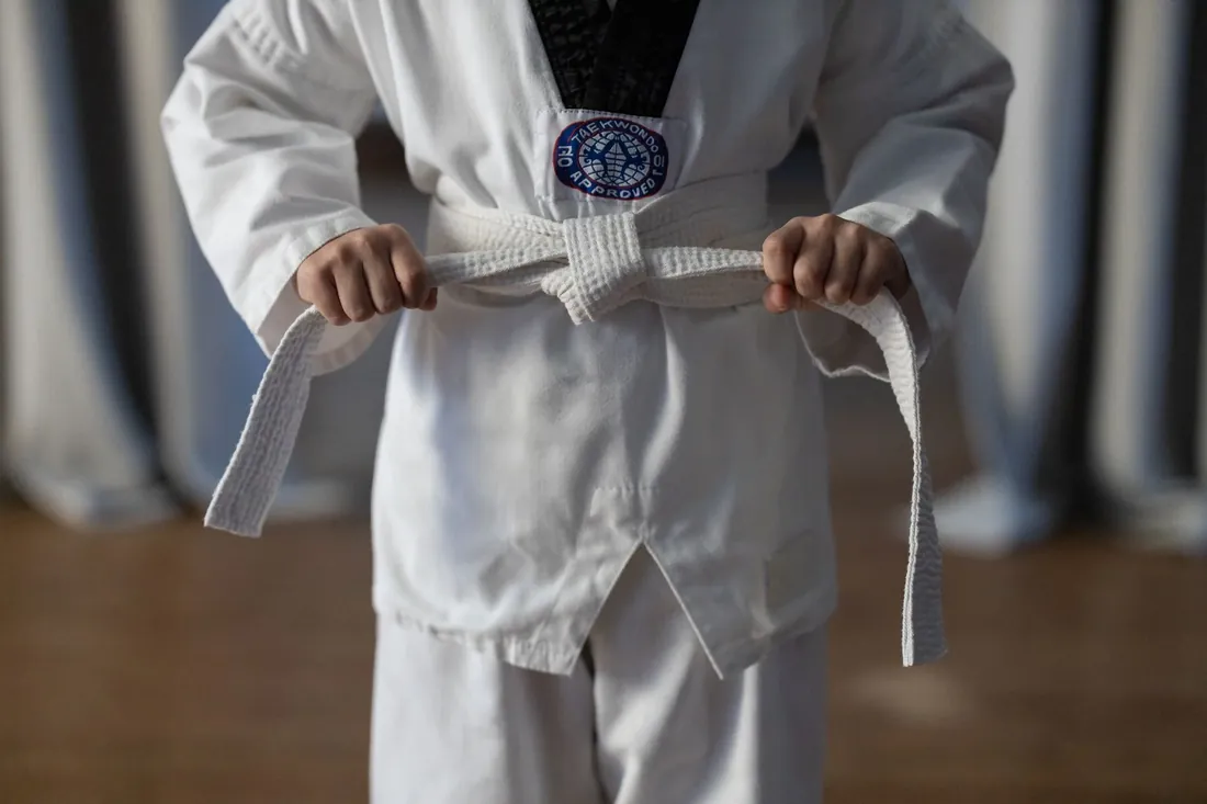 A student tying a white belt in a square knot
