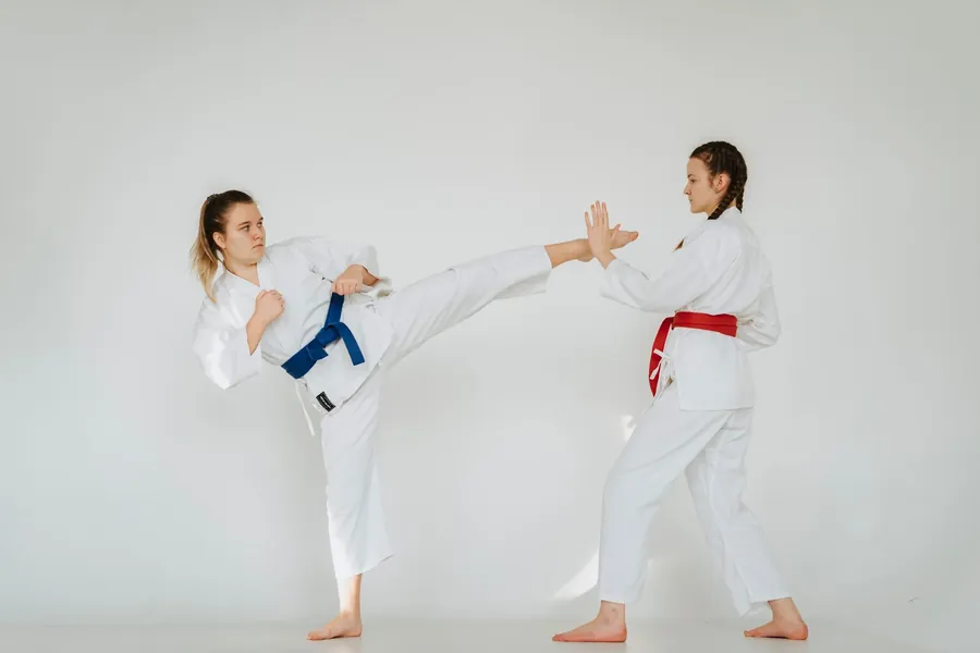 Two teenagers practising a controlled kick and block