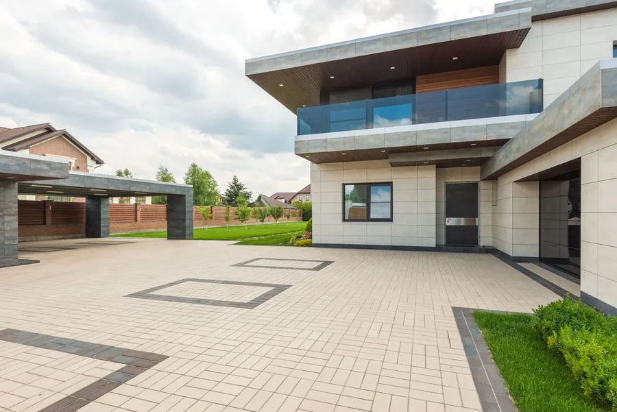 A modern house with a wide light paved driveway