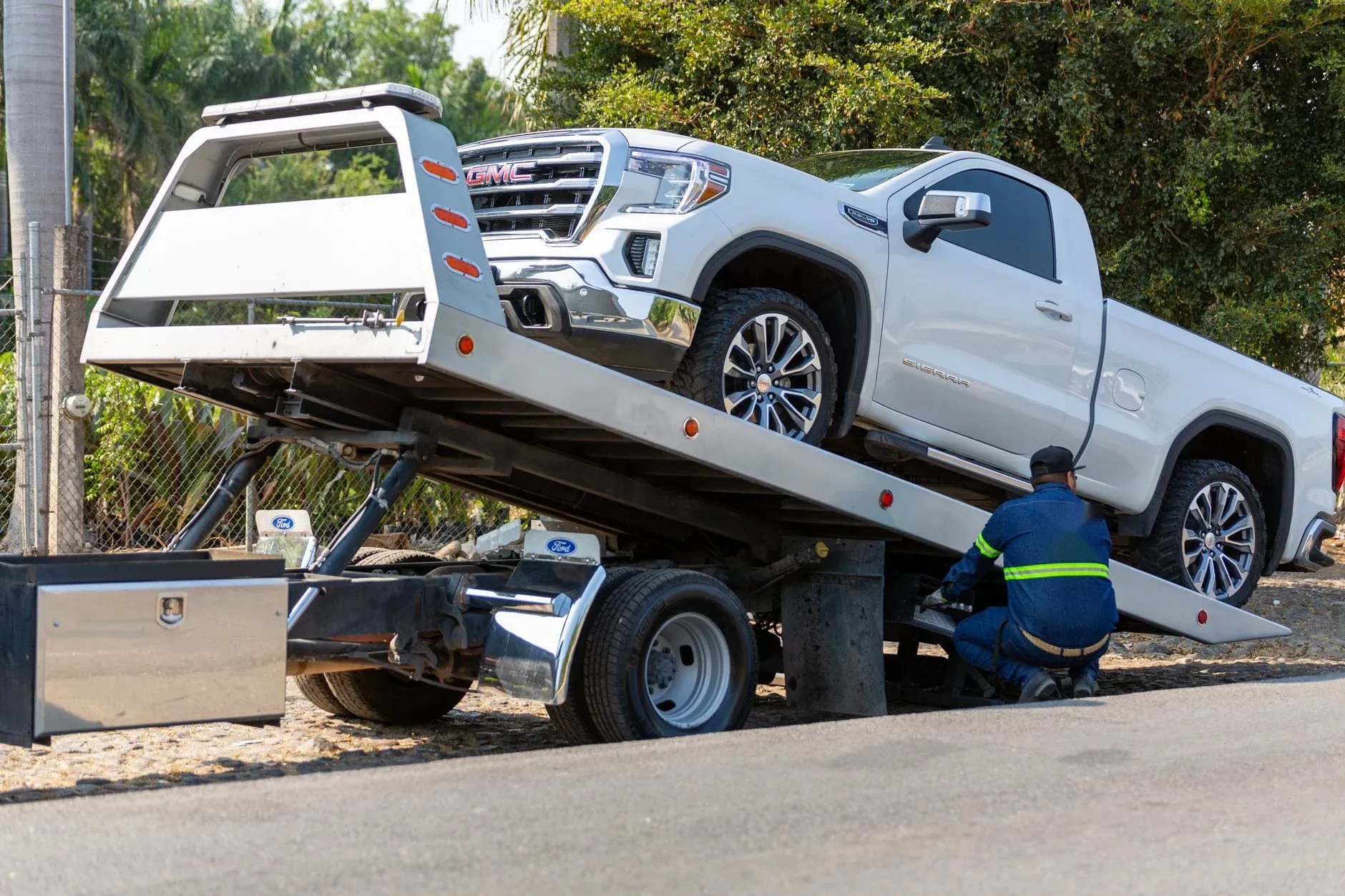 A Tallgrass operator loading a white pickup onto a flatbed