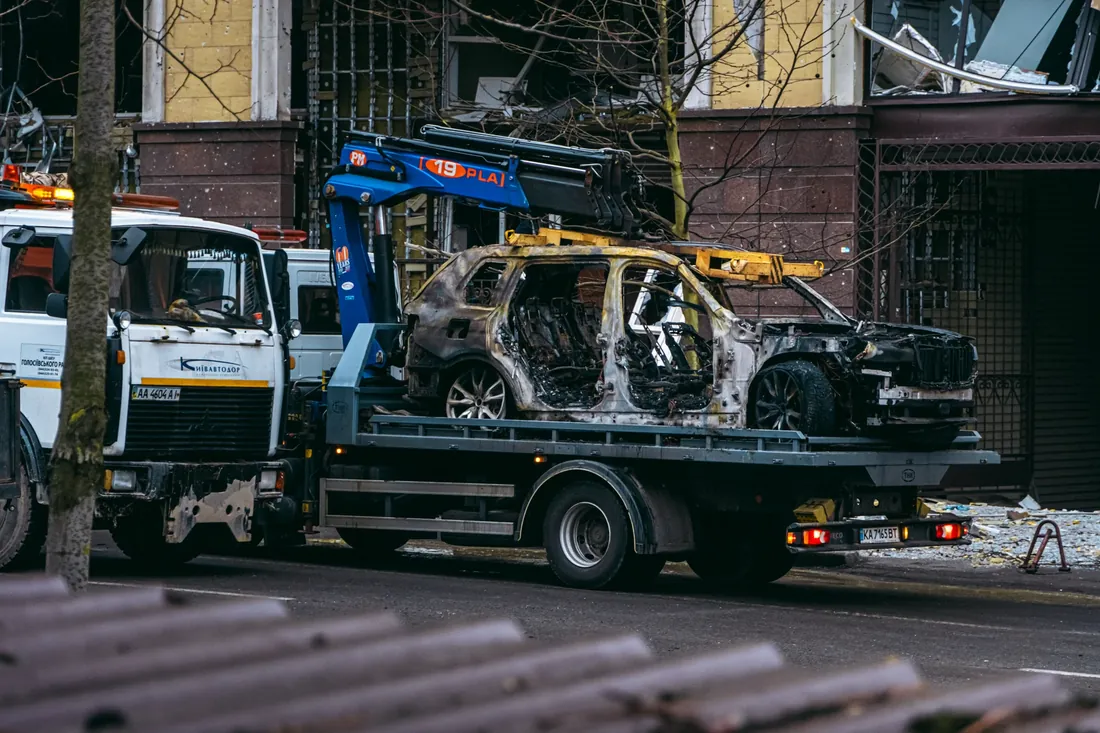 A wrecked car being carried away on a flatbed