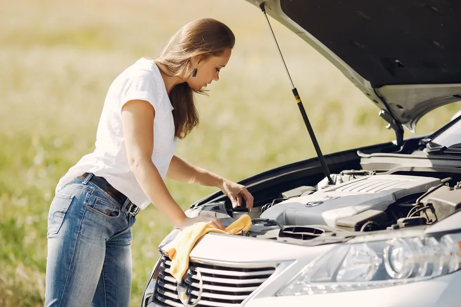 A driver checking under the hood of her car