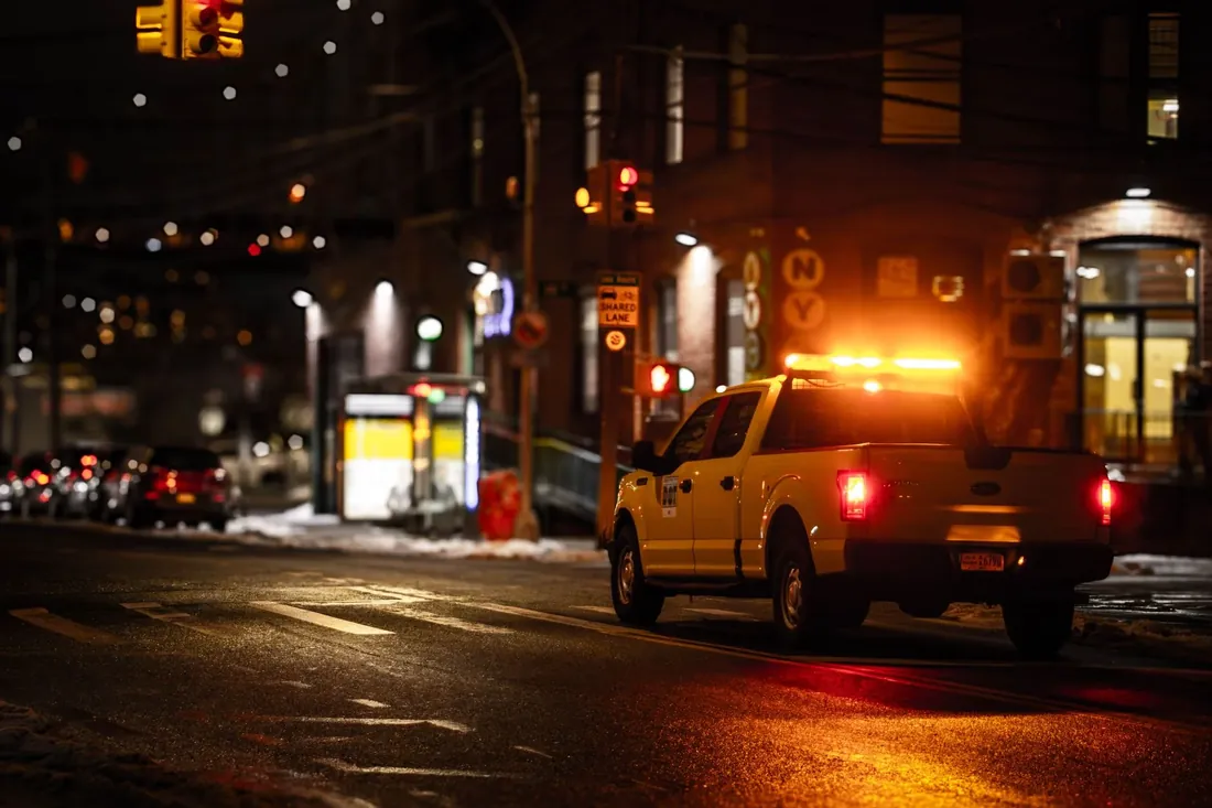 A Tallgrass roadside truck with its amber lights on at a city junction at night