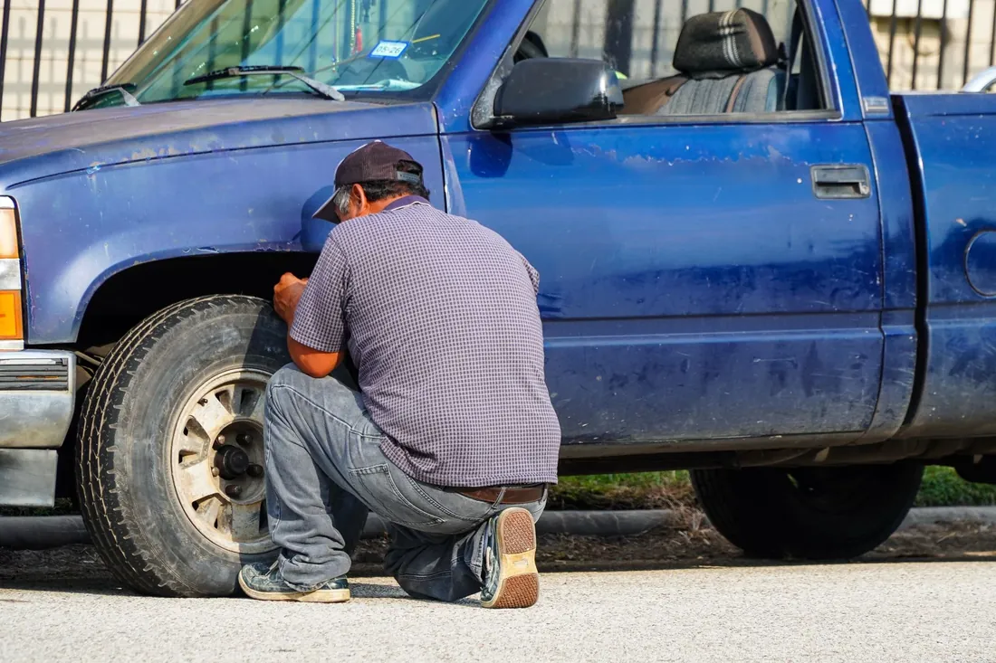 A man changing the tire on a blue pickup