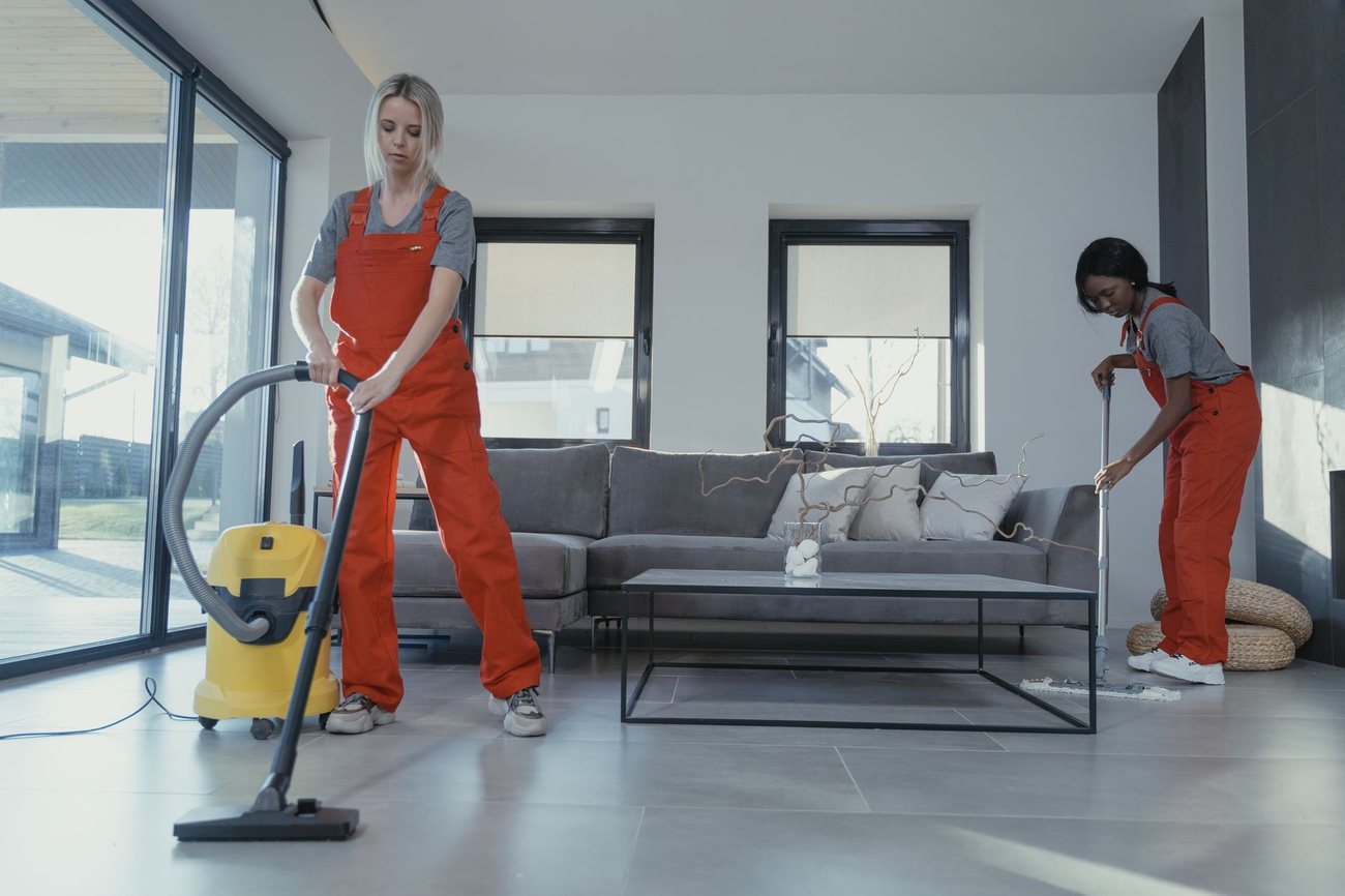 Two cleaners working through a living room