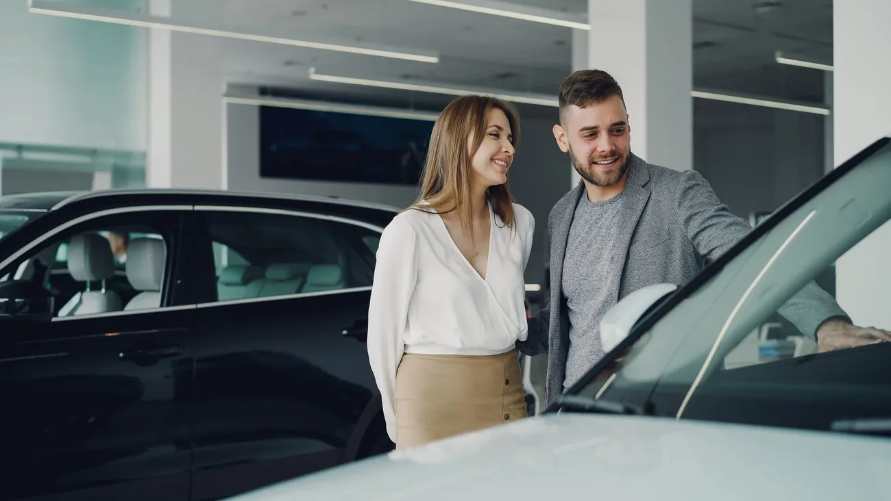 A couple looking over a car with a salesperson in a bright showroom