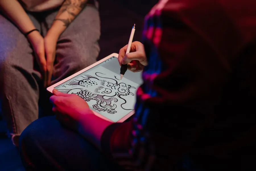 An artist at a desk drawing a design before a session