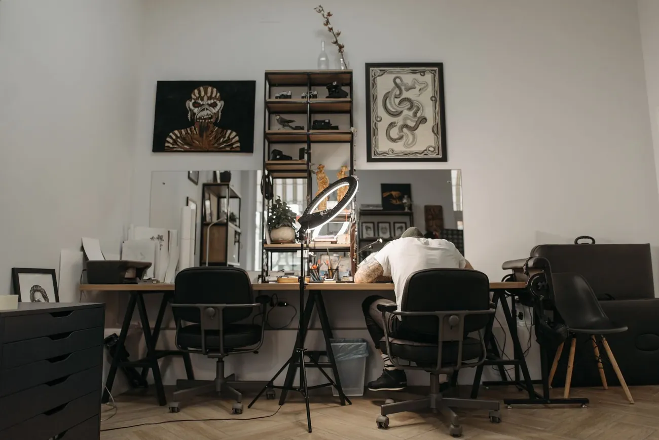 A tattoo studio with a work chair, framed art and plants in the window