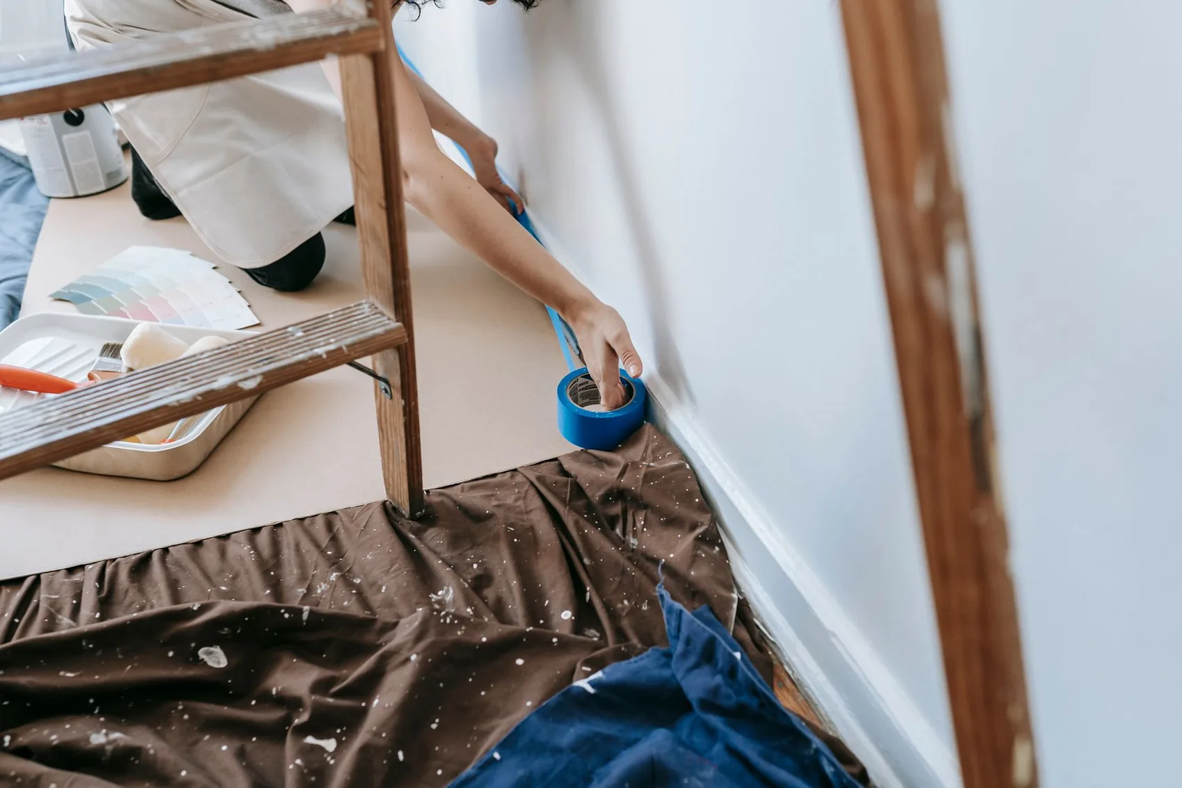 Decorator on a ladder cutting in above a dust sheet