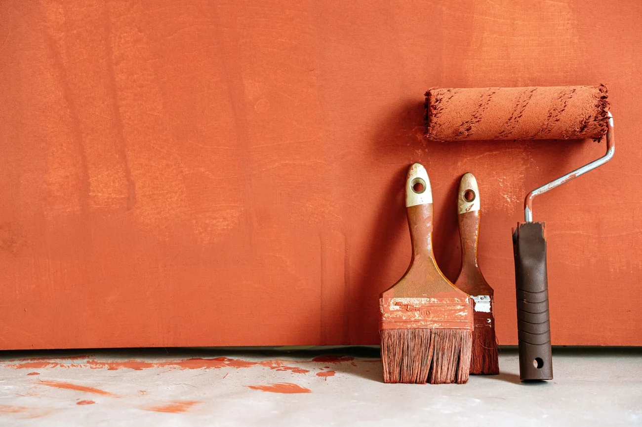 Roller and brushes against a freshly painted wall