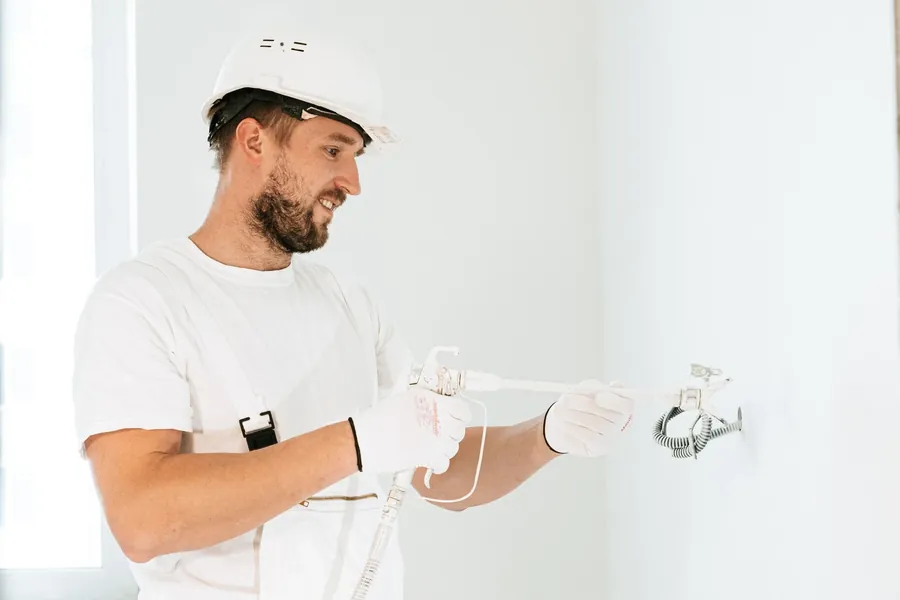A fitter in a white hard hat working on a wall