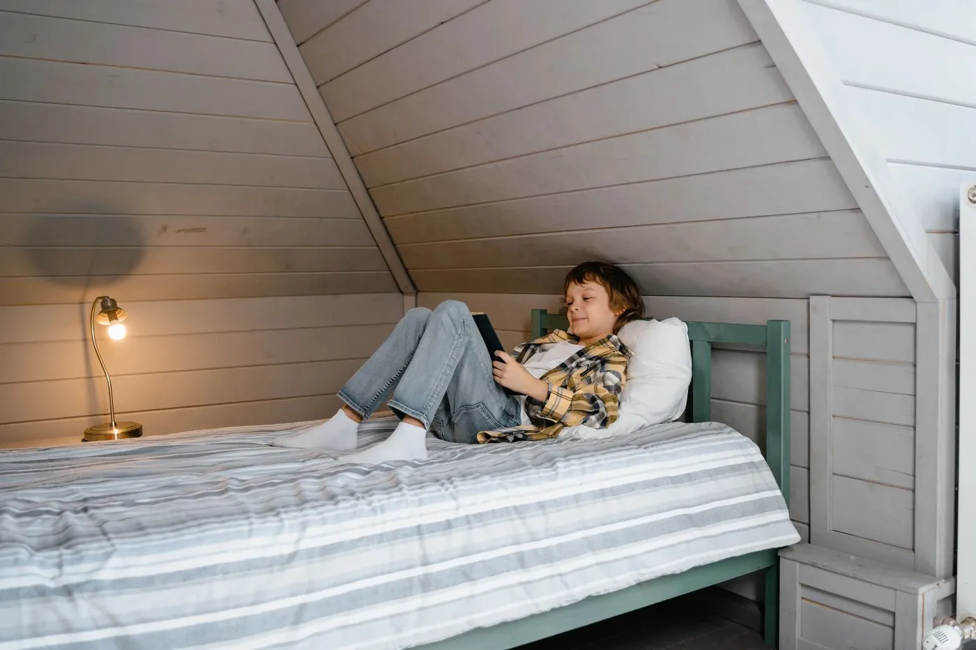A person reading in bed in a warm loft bedroom